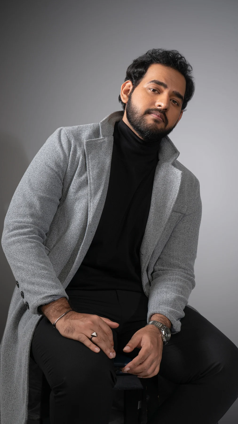 Alii Khan seated in a gray blazer with hands on his knees