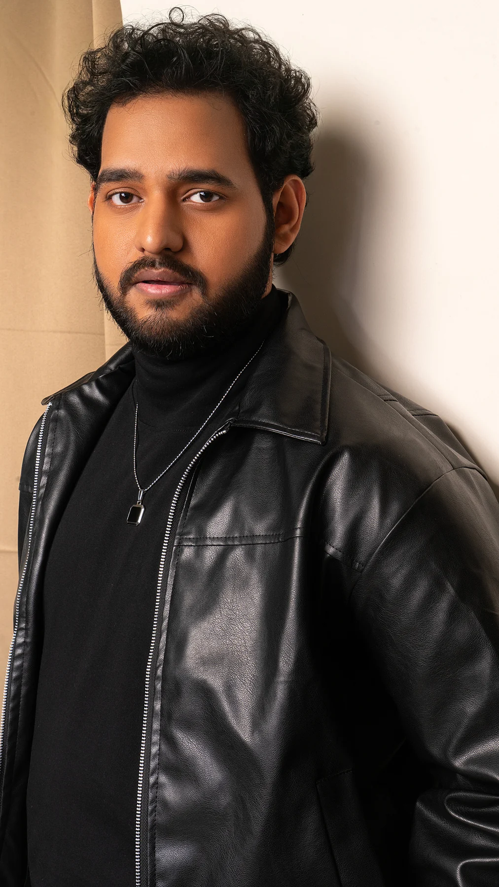 Alii Khan in a black leather jacket beside an arched doorway